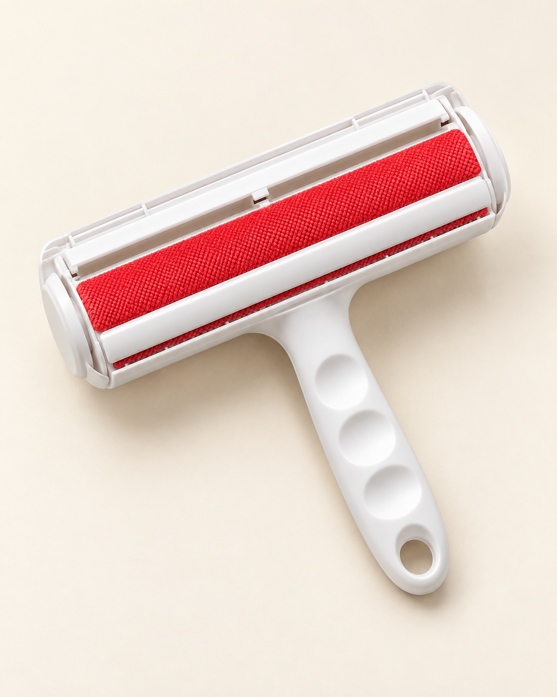 White reusable pet hair remover roller with red textured fabric and a contoured handle on an ivory background.